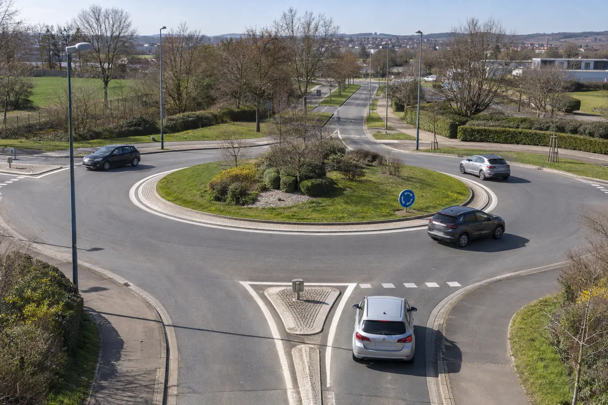 Carrefour giratoire français vu de haut avec des voitures engagées sur l&rsquo;anneau